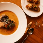 Bouillabaisse im Restaurant und Landhotel Winter auf der Schwäbischen Alb mit Weißwein und Baguette auf dem Tisch im Restaurant.