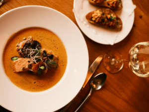 Bouillabaisse im Restaurant und Landhotel Winter auf der Schwäbischen Alb mit Weißwein und Baguette auf dem Tisch im Restaurant.