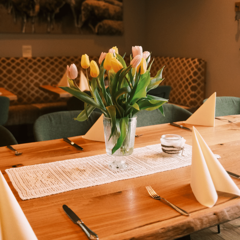 Osterglocken Strauß auf einer langen Restaurant Tafel.