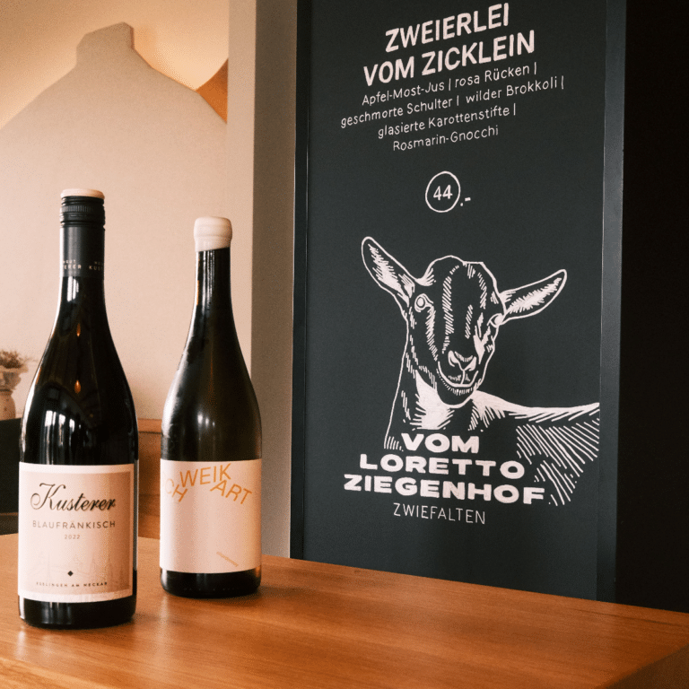 Kreidetafel mit Aufschrift und Weinflaschen.